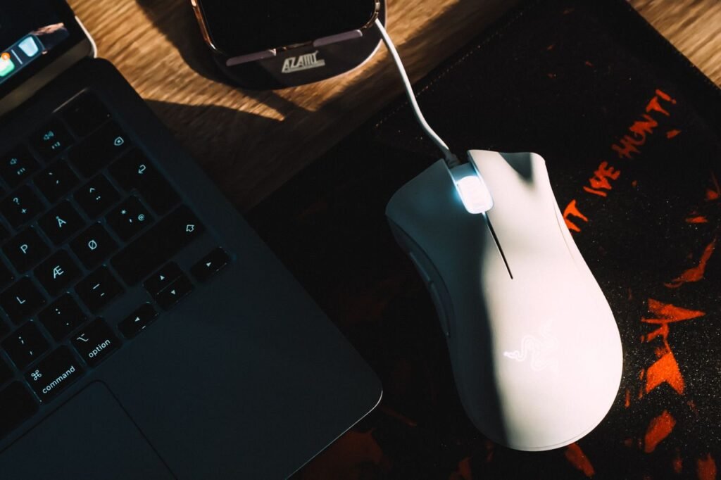 Stylish workspace setup featuring a gaming mouse and laptop with dramatic lighting.
